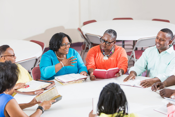 A group of mature black men and women at bible study meeting